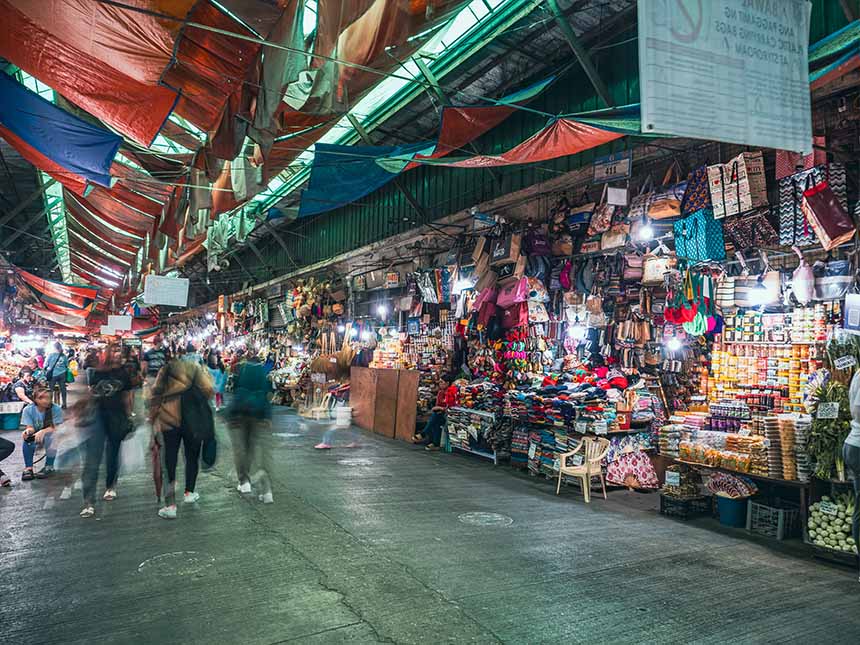 A bustling market scene with people browsing various colorful items and stalls.