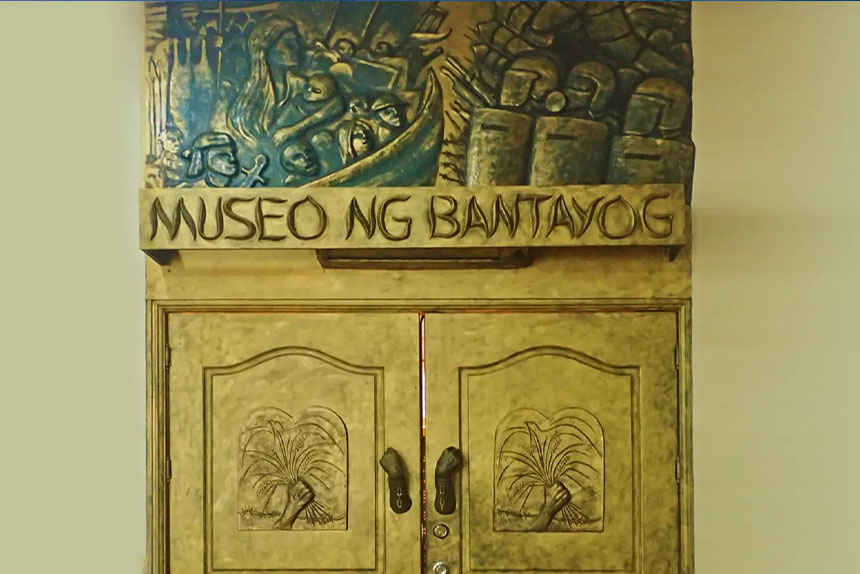 A wooden cabinet featuring an artwork and text, Museo ng Bantayog, on its top.