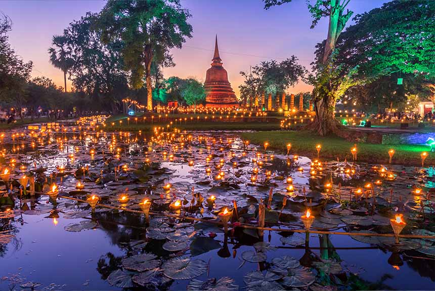 A tranquil pond illuminated by candles, with a pagoda standing gracefully in the background.