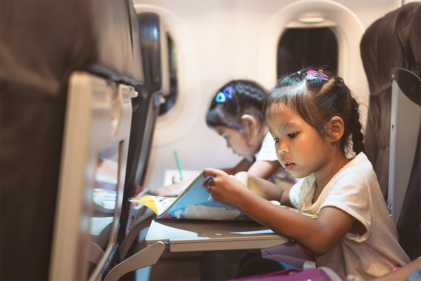 Children seated on an airplane using tray tables during a flight