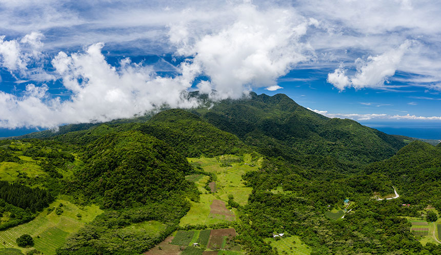 Aerial view of lush green farmland and clouds on the slopes of an active volcano, Mount Hibok-Hibok.