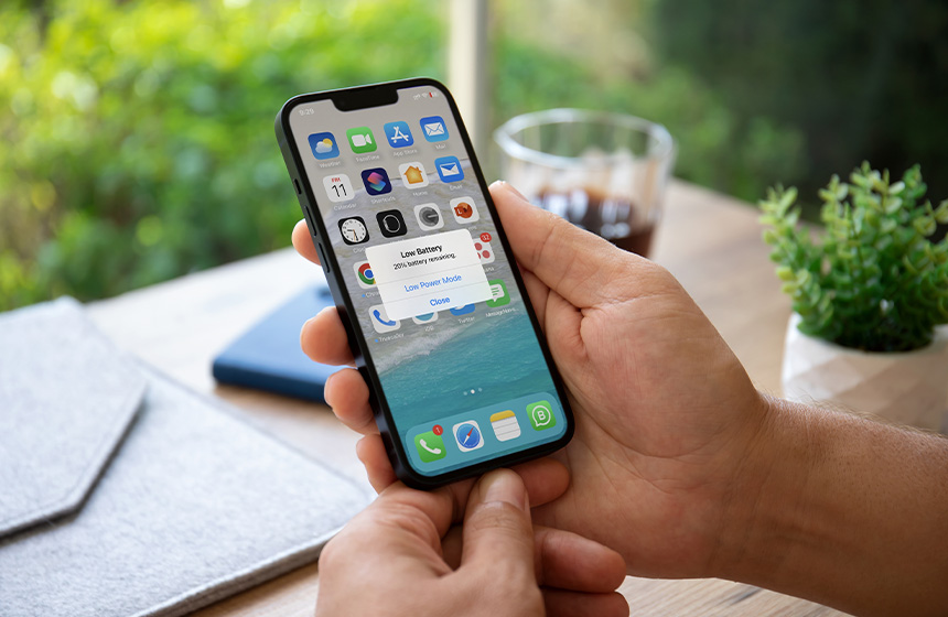 User interacting with an iPhone displaying a low battery warning.