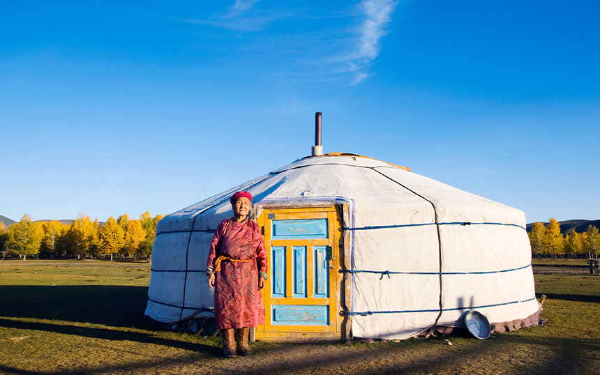 A female local in Mongolia stands in front of a traditional tent.