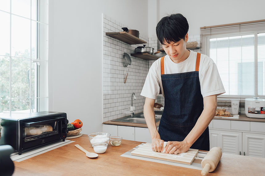 A man kneading some dough in the kitchen.
