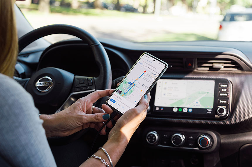 A woman checks her mobile device to help in navigation while driving.