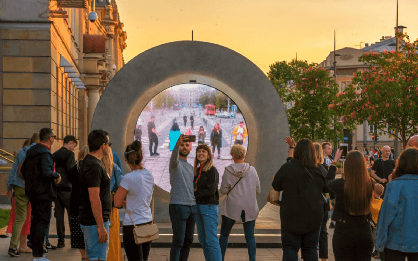 People gather around the Portal installation in Lublin, Poland, taking photos with a live video feed from another city.