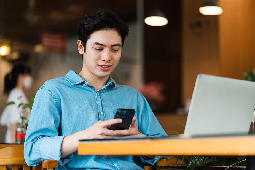 A man in a cafe, engaged with his device, surrounded by a cozy atmosphere.