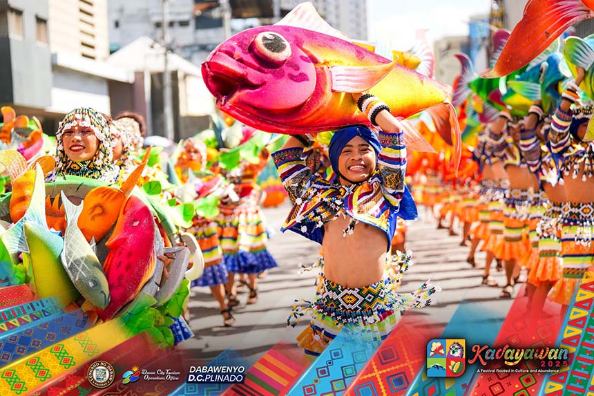 Kadayawan Festival street dancers in colorful costumes carrying props in Davao City.