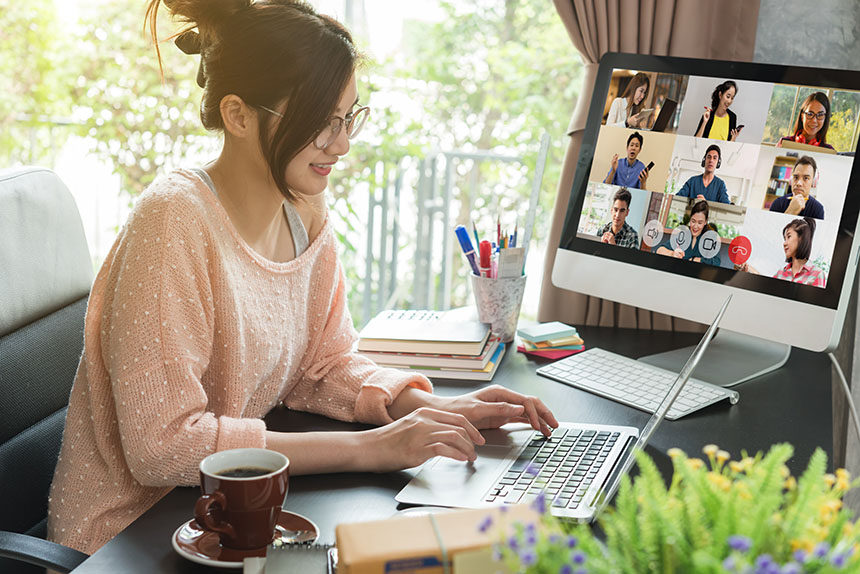 Young Asian woman working from home, on her desk, with two computers.