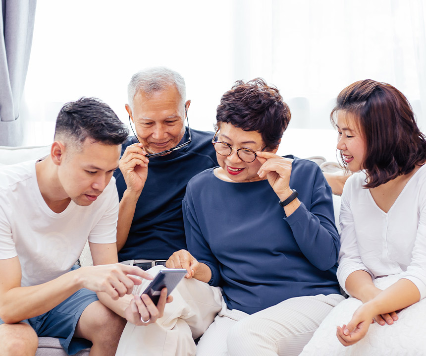 Family gathered around helping mom use a smartphone.