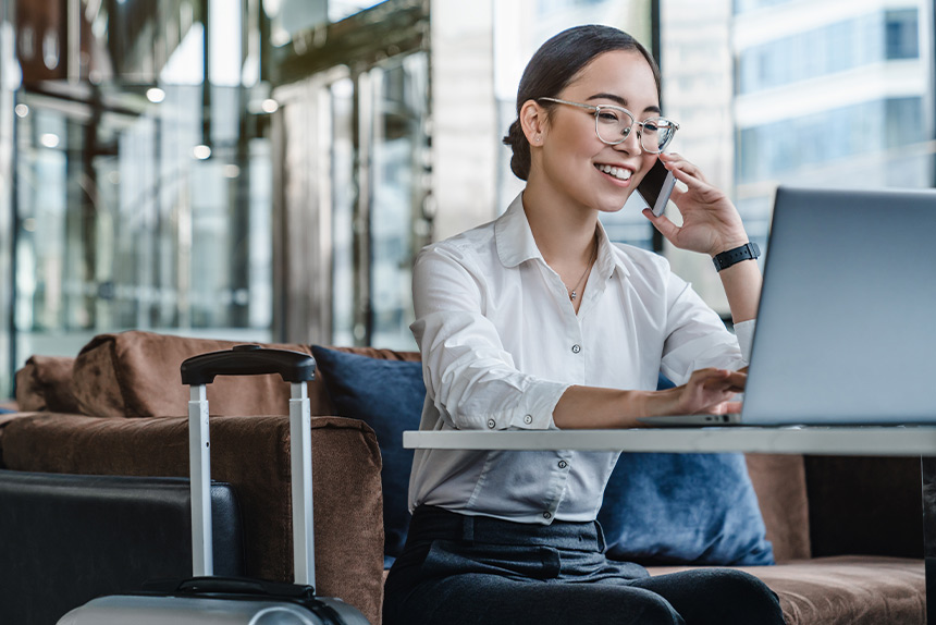 Professional working on a laptop while on a phone call in a flexible workspace.