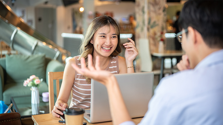 Freelancers discussing work ideas over a laptop in a café setting.