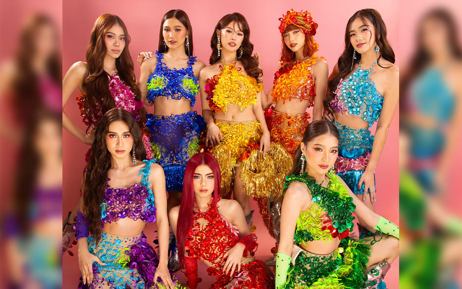 BINI, a Filipino girl group, posing in vibrant, colorful outfits inspired by a rainbow theme against a pink background.