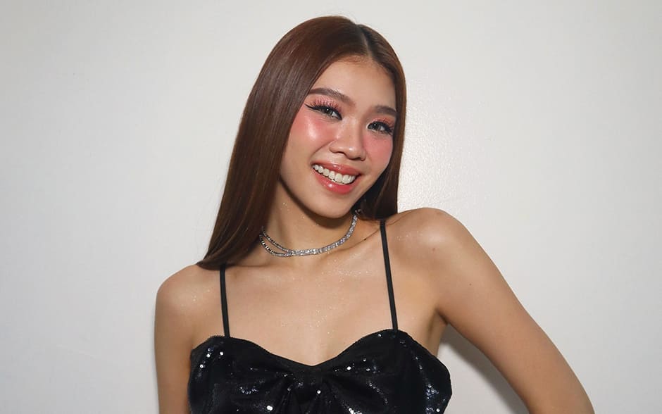 BINI Stacey smiling brightly, wearing a black sequined bow top and a red skirt with studded details.