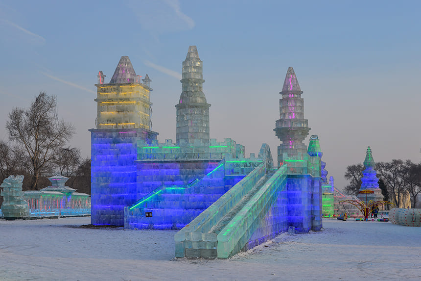 A castle sculpted out of ice with colorful lights.