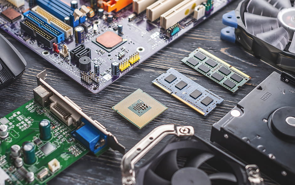 Flat lay of computer components like the CPU, motherboard, and CPU coolers on a dark table surface.