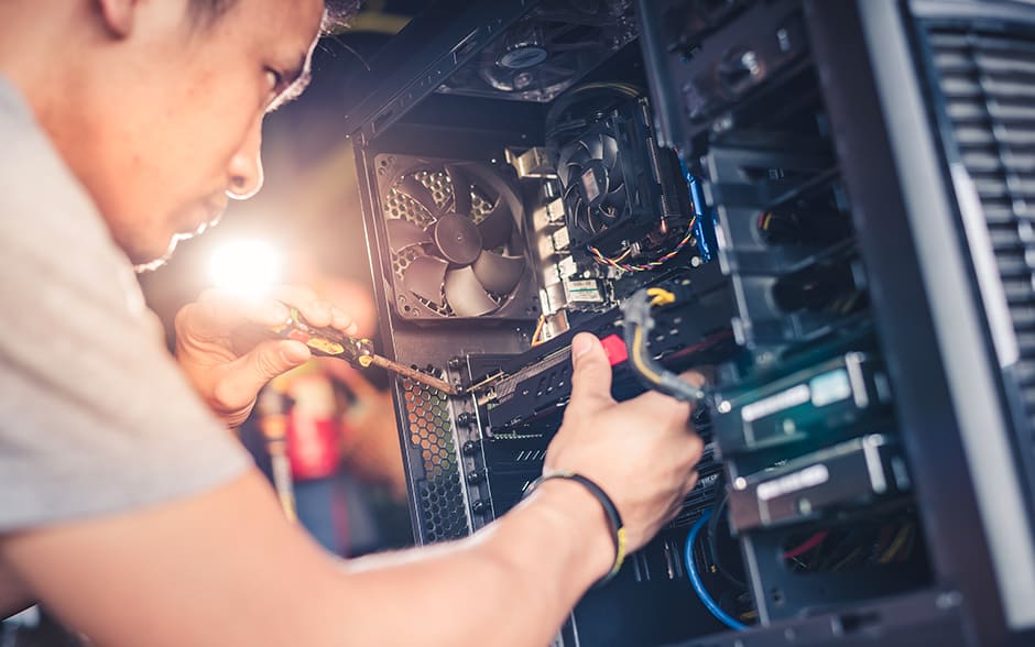 An Asian man using a screwdriver to assemble a PC.