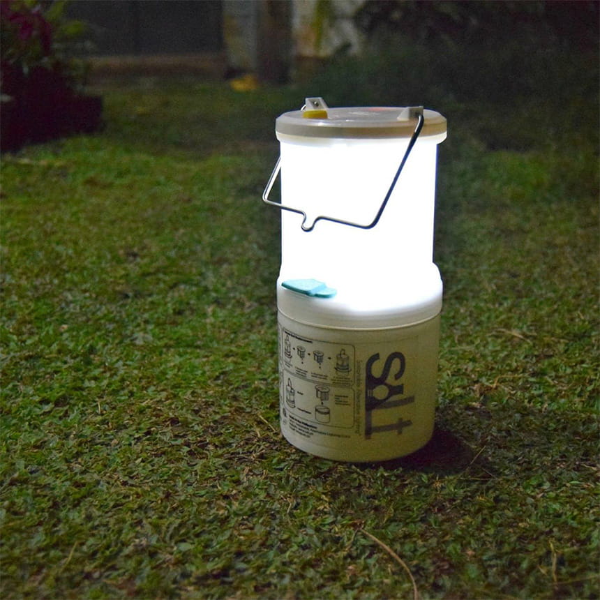 A glowing lantern on a grassy surface in a dim environment.