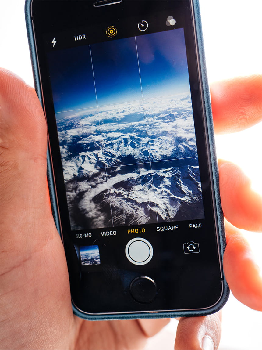 Smartphone displaying an aerial photo of snow-covered mountains in its camera app.