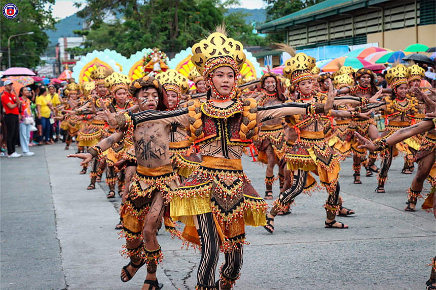 Street parade with performers in colorful traditional costumes and headdresses.