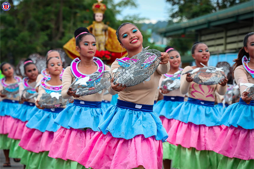 A parade with dancers in colorful outfits holding decorative baskets.