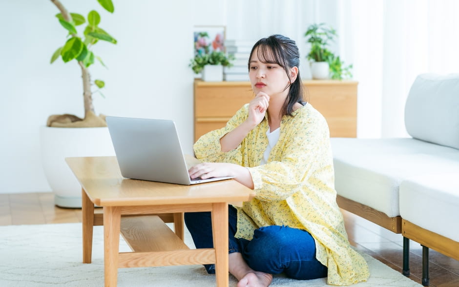 Serious woman on a couch, using a laptop in a cozy living room.