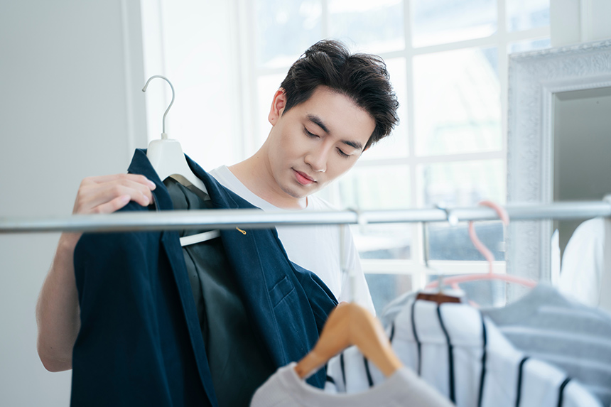 Person reviewing clothing items in a closet at home.