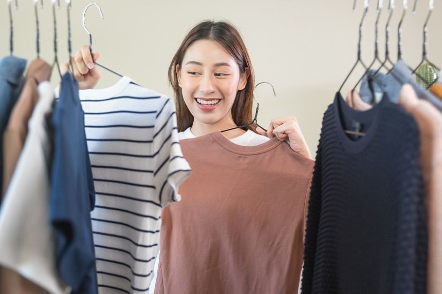 Asian woman holding two shirts.