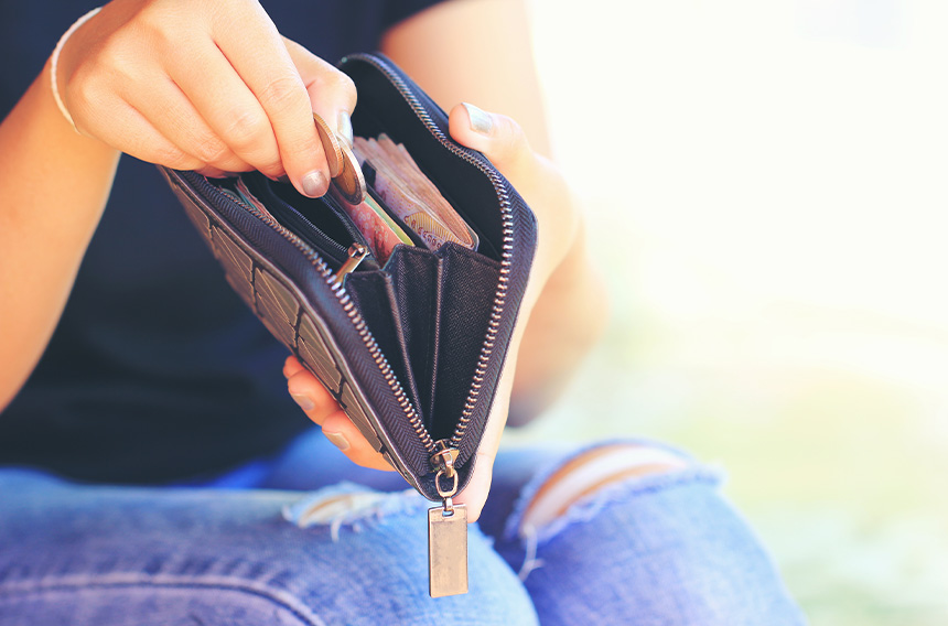 A person holding a wallet with cash while managing transportation expenses.