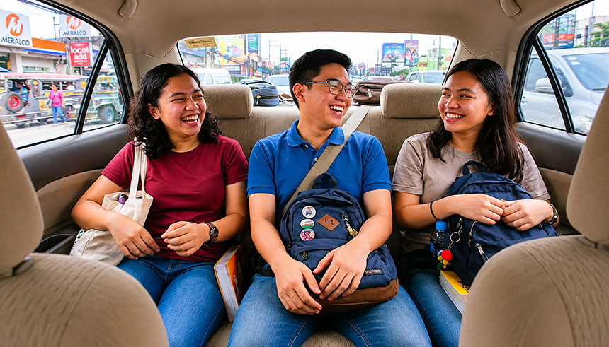 Three Filipino commuters sharing a ride together inside a car during a city trip.