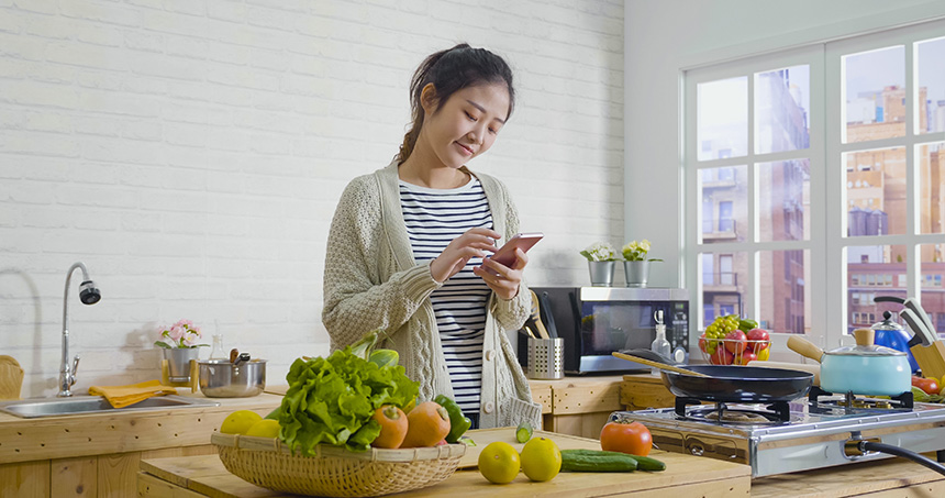 Woman using a mobile app while preparing food at home.