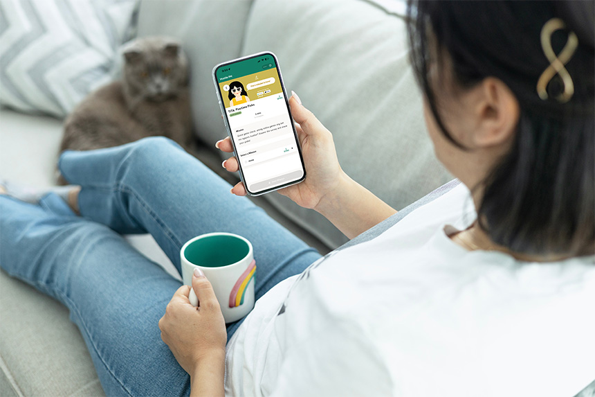 Woman completing tasks on her smartphone while relaxing with her cat.