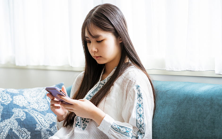Woman on the couch, scrolling on her phone