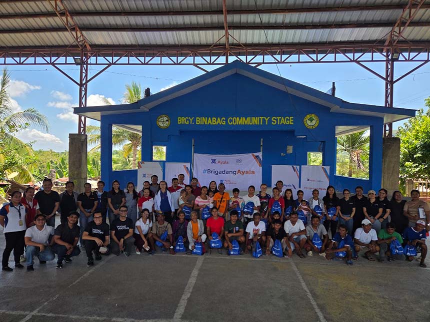 Globe and Ayala Foundation representatives with resident families holding shelter kits and Go Bags at Binabag Community Stage in Bogo City, Cebu.