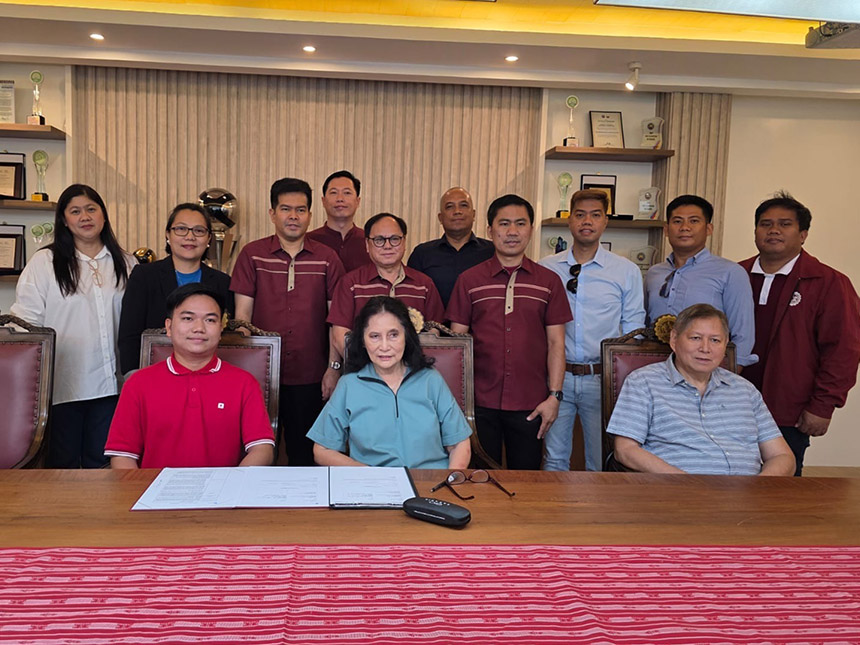 Group portrait of representatives from Globe and MSEUF-Lucena Campus gathered around a boardroom table featuring the signed partnership agreement for a new on-campus cell site.