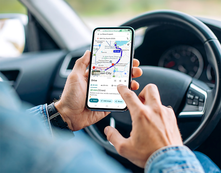 Person using a navigation app on a smartphone while sitting in the driver's seat of a car.