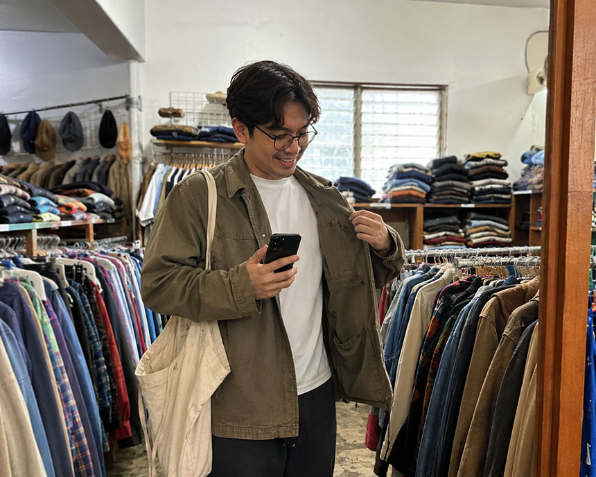 Man trying on a jacket while shopping inside a store.