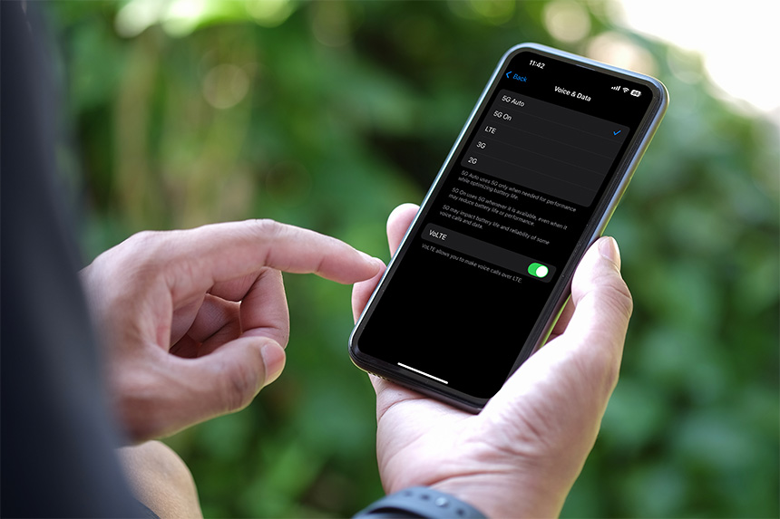 Person using a smartphone to check their deviceâs network type outdoors.
