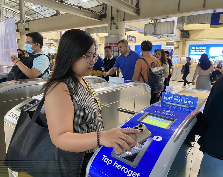 Commuter using her smartphone to tap in at an MRT station gate.