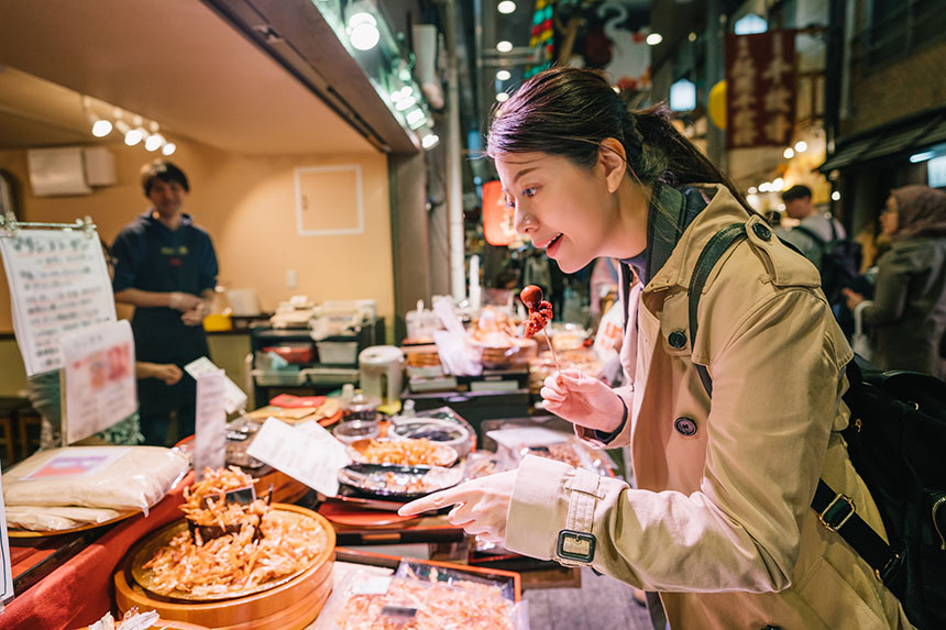 Female tourist points to a dish in a food street stall in Japan, representing how GCash is accepted by local merchants around the world.