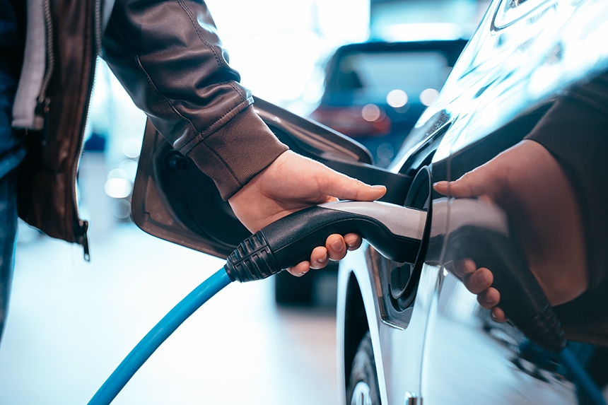 A driver charging a hybrid or electric vehicle at a public charging station.