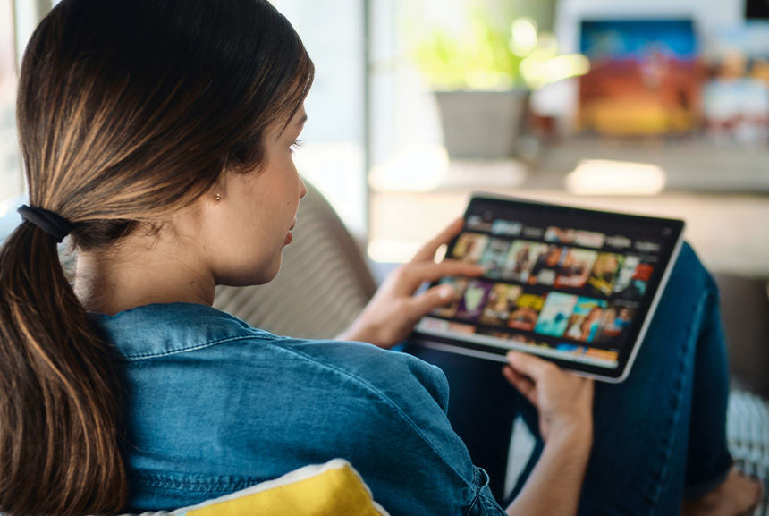 A woman browsing a digital movie catalog on her tablet.