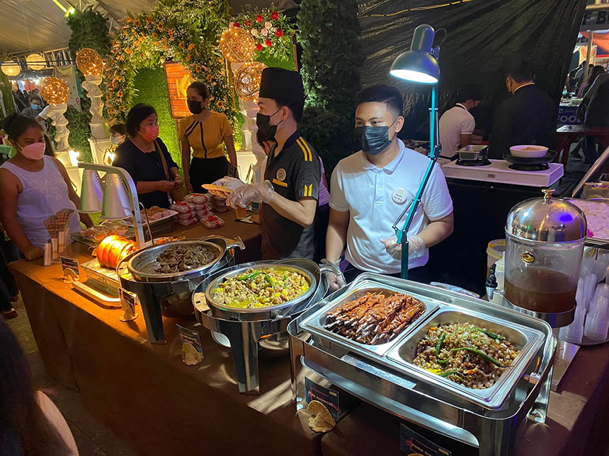 Caterers standing in front of trays filled with food at Boholâs Fusion Nights market.