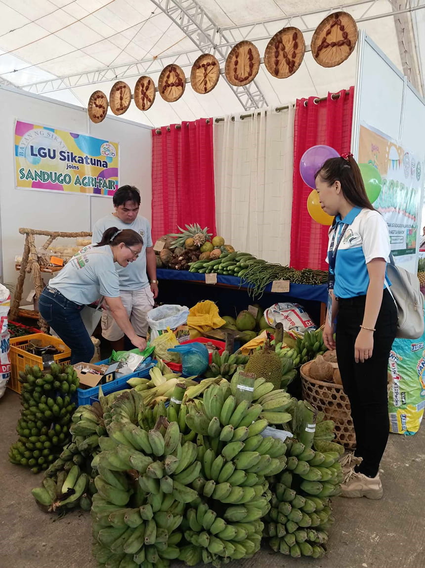 Shoppers at a stall filled with bananas and other produce at Sandugo Agri-Fair.