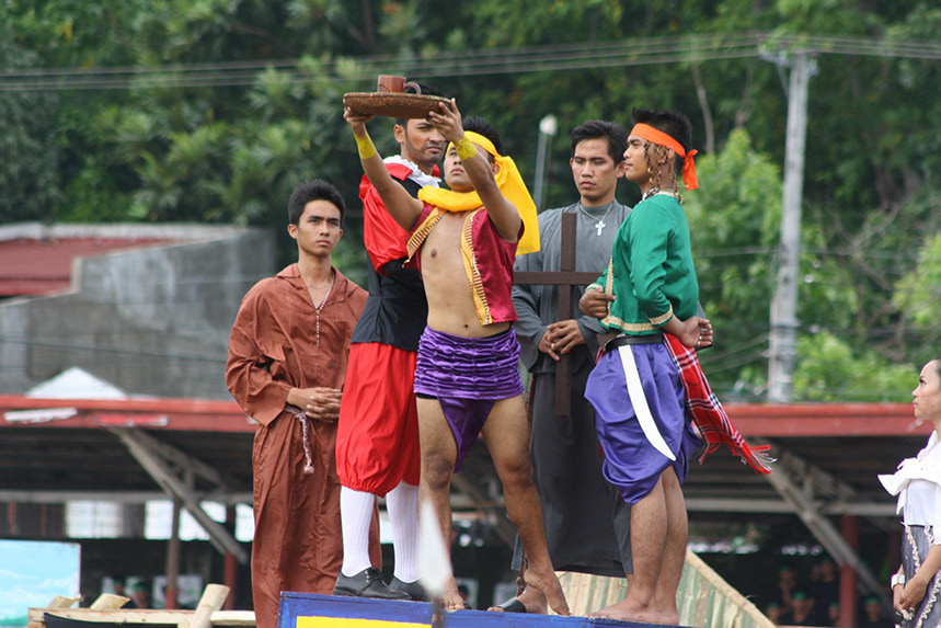 Sandugo festival performer in traditional costume raises a cup that symbolizes the blood compact.