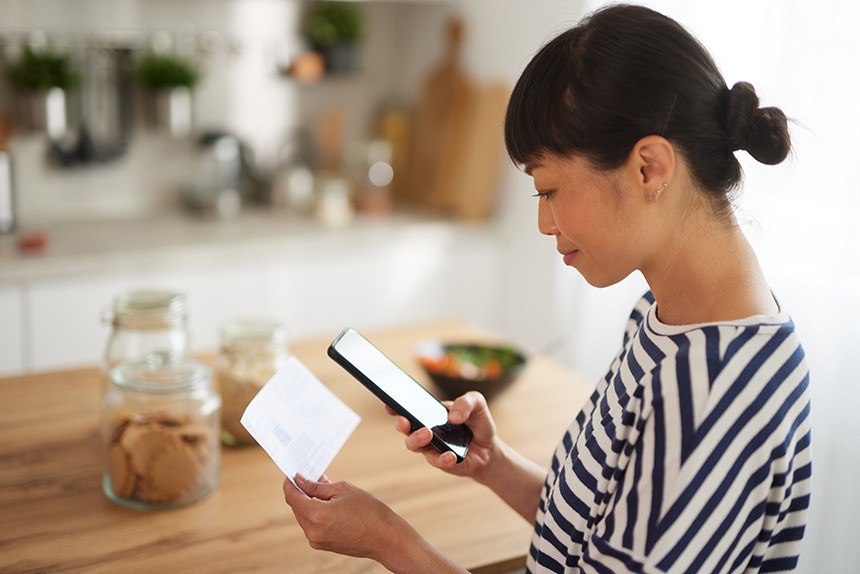 Person reviewing a note while using a smartphone.