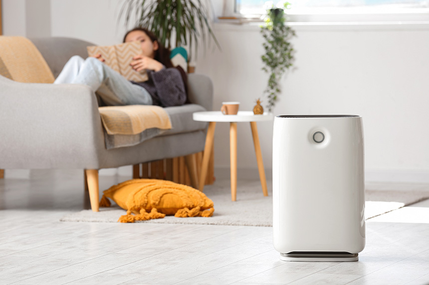 Woman lounging on a sofa with an air purifier in the foreground.