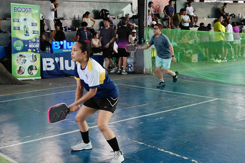 Two players engaged in a Pickleball match inside a spacious indoor arena.