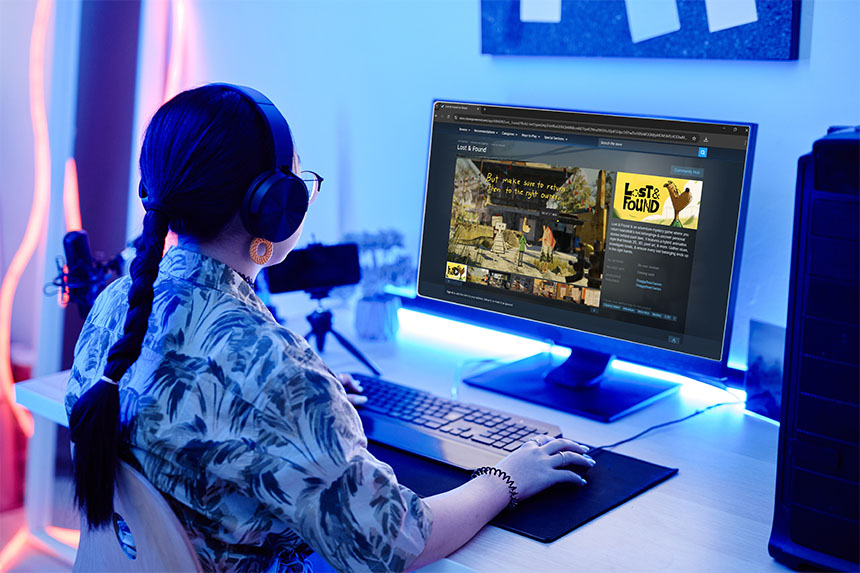 A woman wearing headphones is seated at a computer, engaged in a game.