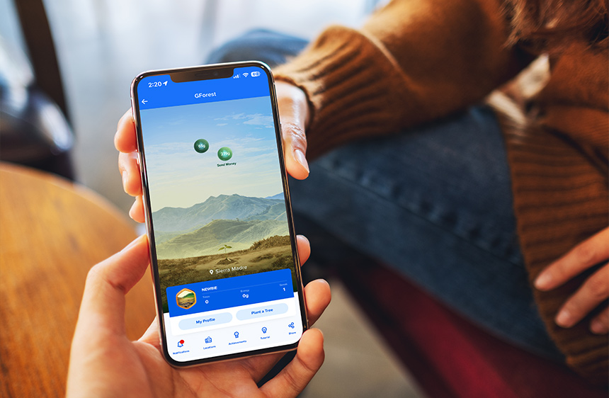 Person holding a smartphone displaying the GForest feature in the GCash app.